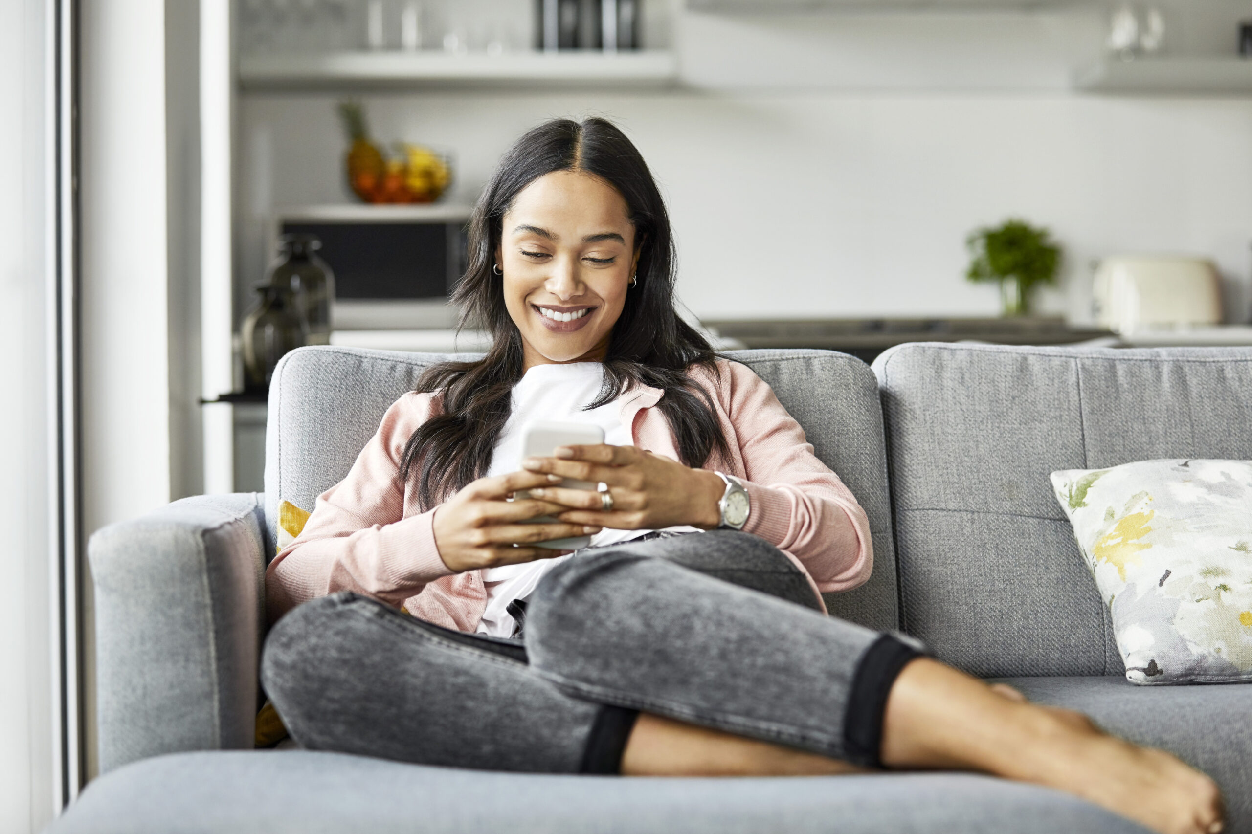 Happy woman text messaging on smart phone at home