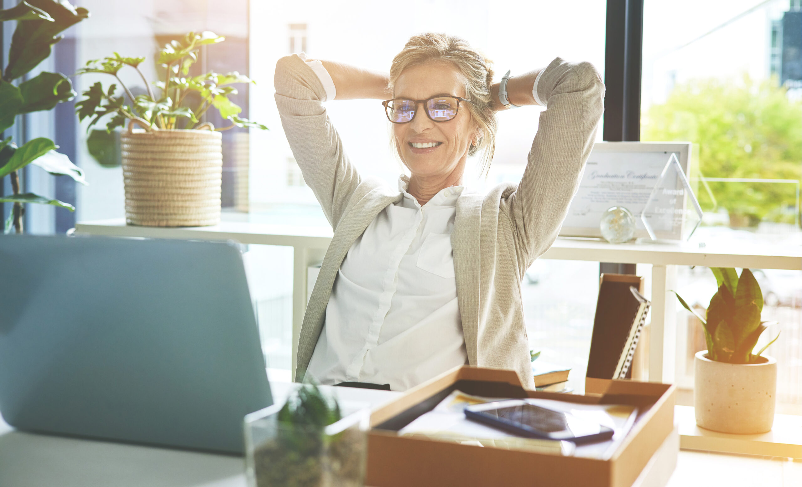 Business woman feeling accomplished and enjoying a relaxing break to stretch with hands behind her head in an office.