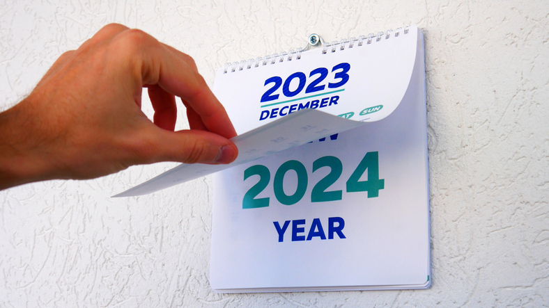 A male hand flips through a December page 2023 of the wall calendar followed by the title page of a new calendar 2024