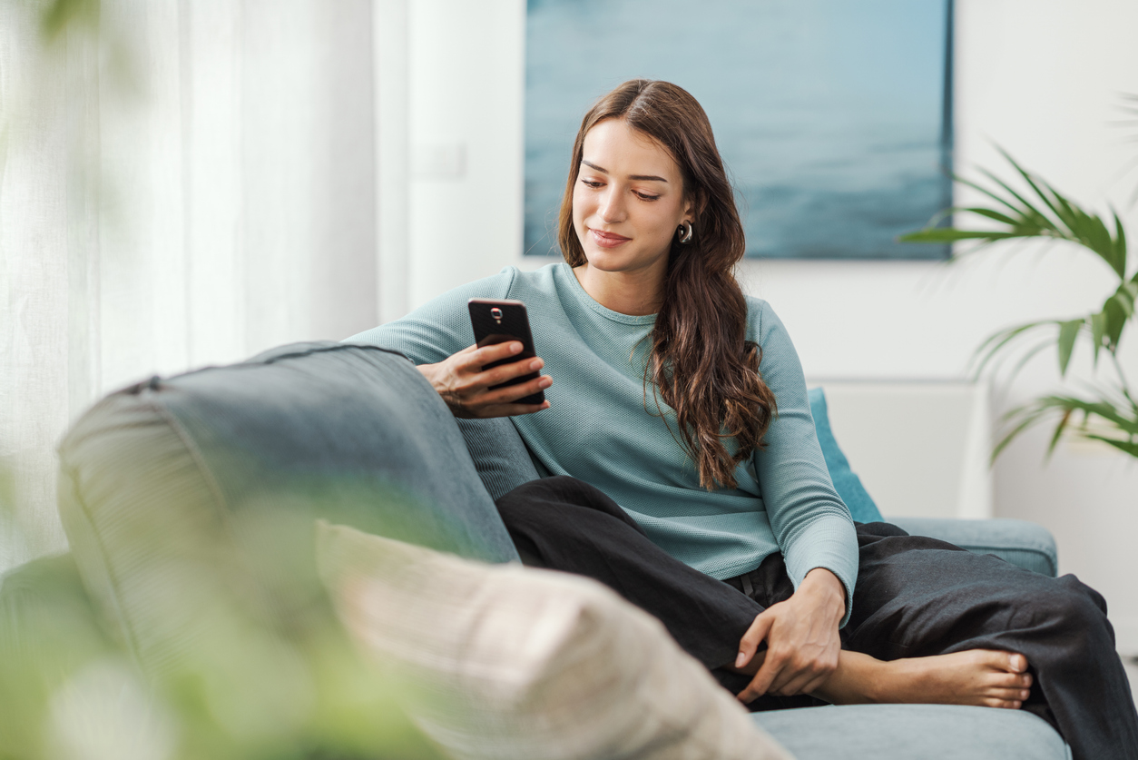 Woman on couch viewing giving form on her smartphone